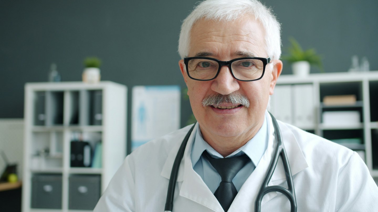 Smiling doctor with glasses and stethoscope around his neck.